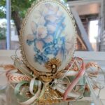 Gallary egg with pearl and jewel outline, sitting atop a golden base with ribbon.