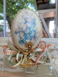 Gallary egg with pearl and jewel outline, sitting atop a golden base with ribbon.