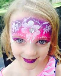 A little girl with face paint around the forehead with flowers and stems.